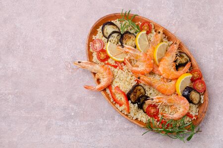Unpeeled boiled shrimp with bulgur and vegetables in a dish on a slate background. Selective focus.の写真素材