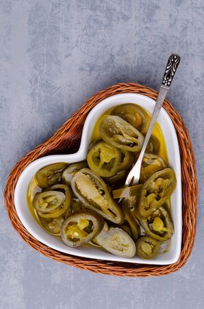Slices of green pepper pickles in a bowl on a wooden background. Selective focus.の写真素材