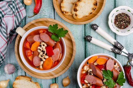 Stewed beans with sausages and vegetables in a ceramic dish. Selective focus.の写真素材