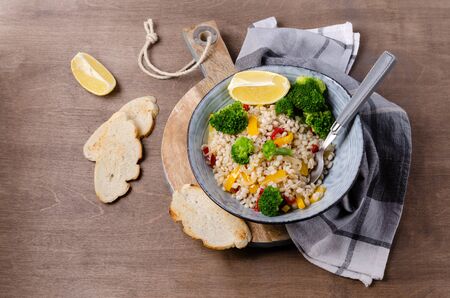 Warm pearl salad with vegetables on a wooden background. Selective focus.の写真素材