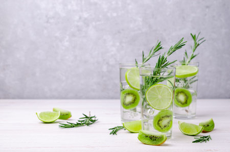 Transparent drink with fruit and rosemary in glass on a light background. Selective focus.の写真素材