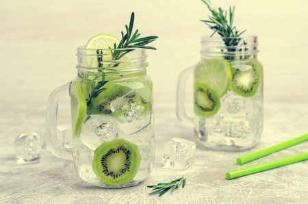 Transparent drink with fruit and rosemary in glass on a light background. Selective focus.の写真素材