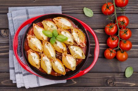 Pasta stuffed with ricotta and spinach in tomato sauce in a ceramic dish on a wooden background. Selective focus.の写真素材