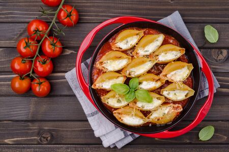 Pasta stuffed with ricotta and spinach in tomato sauce in a ceramic dish on a wooden background. Selective focus.の写真素材