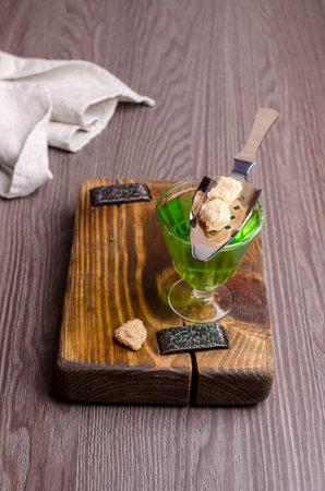 Green liquid in a glass with sugar cubes on a dark wooden background. Selective focus.の写真素材