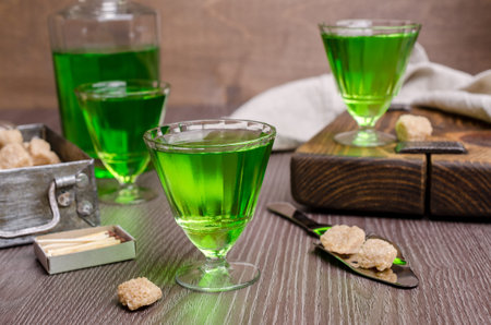 Green liquid in a glass with sugar cubes on a dark wooden background. Selective focus.の写真素材