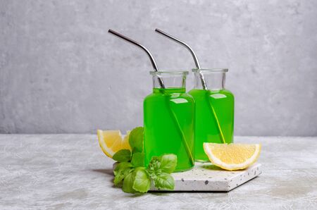 Green liquid in a glass bottle on a slate background with lemon and basil. Selective focus.の写真素材