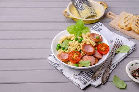 Traditional pasta with sausages and vegetables in a bowl on a wooden background. Selective focus.の写真素材
