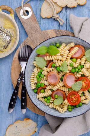 Traditional pasta with sausages and vegetables in a bowl on a wooden background. Selective focus.の写真素材
