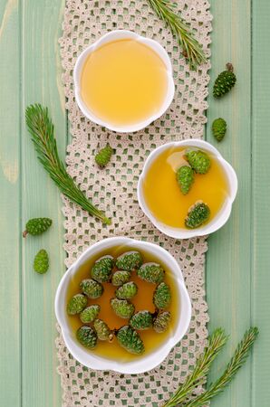 Green cones in yellow syrup in a ceramic dish on a wooden background. Selective focus.の写真素材