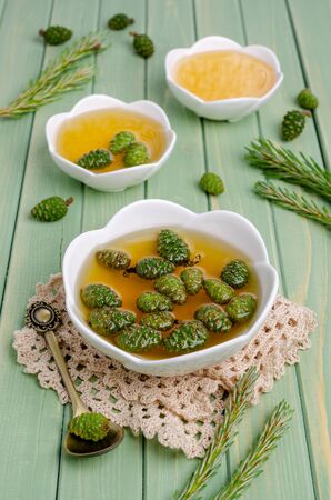 Green cones in yellow syrup in a ceramic dish on a wooden background. Selective focus.の写真素材
