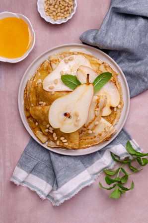 Crepes with pears, nuts and honey in a dish on a slate background. Selective focus.