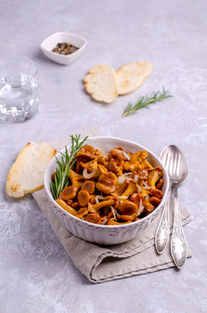 Fried chanterelle mushrooms with onions and rosemary on a gray slate background. Selective focus.の写真素材