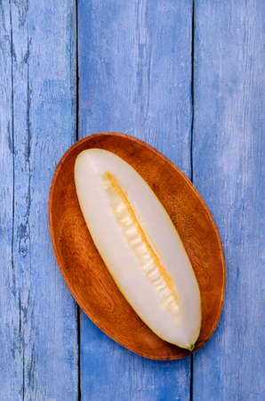 Slices of raw melon on an old blue wooden background. Design concept. Selective focus.の写真素材