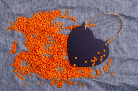 Dry red lentils on a blue textile background with an empty sticker. Top view. Design concept. Copy space.の写真素材