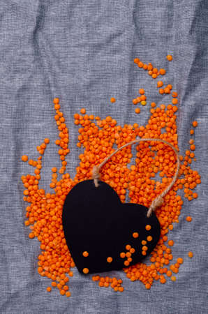 Dry red lentils on a blue textile background with an empty sticker. Top view. Design concept. Copy space.の写真素材