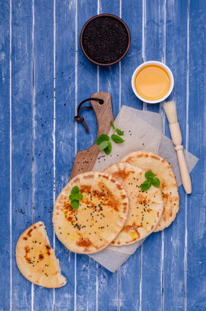 Traditional flatbread with oil, sesame and mint on a blue wooden background. Selective focus.