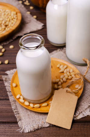 Milk pine nut in glass on old textiles and dark wood background. Selective focus.の写真素材