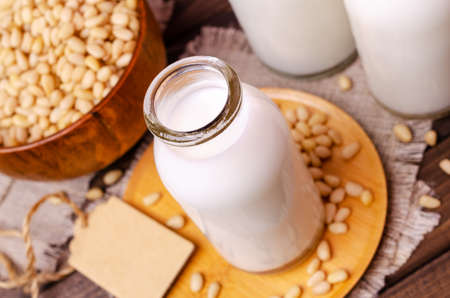 Milk pine nut in glass on old textiles and dark wood background. Selective focus.の写真素材