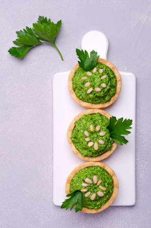 Tartlets with green cream and nuts on a light stone background. Selective focus.の写真素材