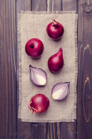 Raw red onion on textile burlap on a dark wooden background. Selective focus.の写真素材