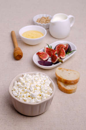 Cottage cheese with fig slices, nuts and honey in a dish on a textile background. Selective focus.の写真素材