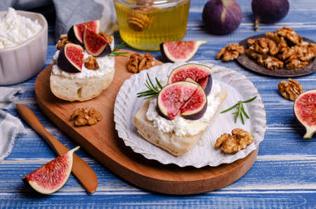 Sandwich with white cream, figs and honey on a blue wooden background. Selective focus.の写真素材