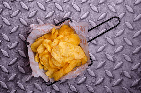Potato chips in a basket on a metal background. Selective focus.の写真素材