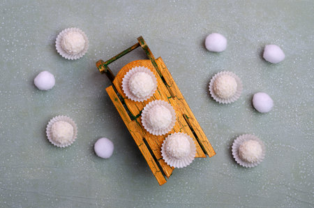 White candy with coconut shavings on a green slate background. Design concept. Selective focus.