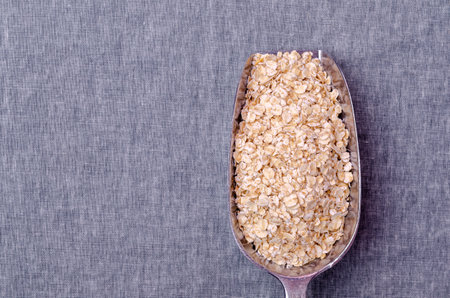 Dry oat flakes in a metal scoop on a textile background. Selective focus.の写真素材