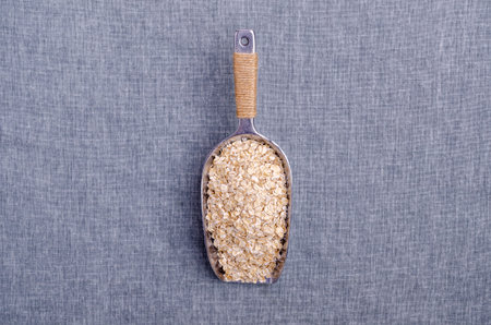 Dry oat flakes in a metal scoop on a textile background. Selective focus.