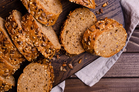 Slices of wholegrain bread with seeds on a dark wooden background. Selective focus.