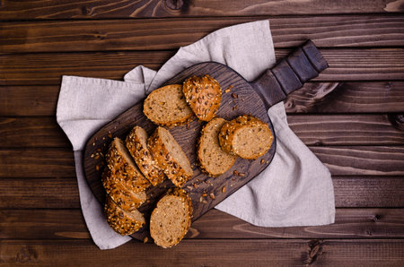 Slices of wholegrain bread with seeds on a dark wooden background. Selective focus.