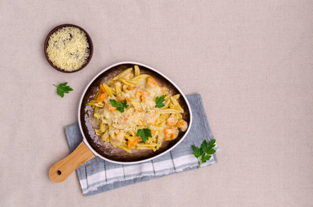 Pasta with pumpkin in white sauce in a ceramic dish on a textile background. Selective focus.の写真素材
