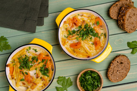 Pasta casserole with vegetables in a ceramic dish on a wooden background. Selective focus.