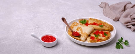 Fried crepes with red fish roe in a ceramic dish on a light cement background. Selective focus.の写真素材