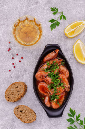 Unpeeled cooked prawns in a spicy sauce with lemon and parsley. Selective focus.の写真素材