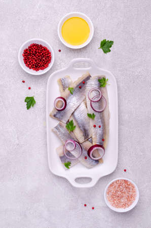 Salted herring fillet with spices on a gray background. Selective focus.の写真素材