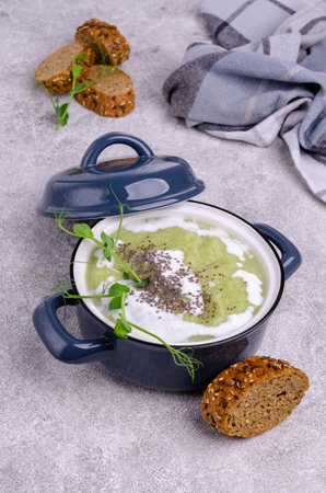 Thick cream soup of green vegetables with white sauce, chia seeds and pea sprouts on a gray background. Selective focus.の写真素材