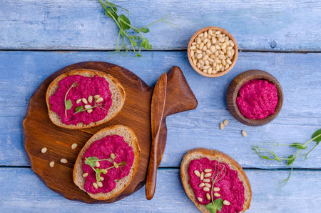 Three sandwiches with beetroot paste, pine nuts and pea sprouts. Blue wooden background. Top view....