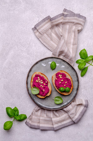 Three sandwiches with beetroot paste, pine nuts and basil. Gray background. Top view. Selective...
