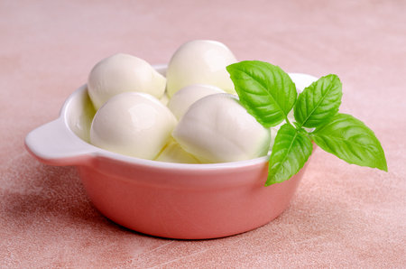 Fresh mozzarella cheese with salad ingredients. Pink background. Top view. Selective focus.