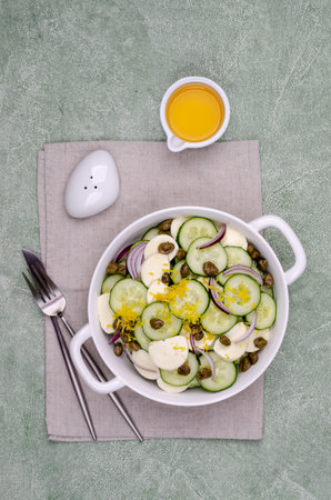 Salad of cucumbers, cheese, capers and lemon zest on a green background. Top view. Selective focus.の写真素材