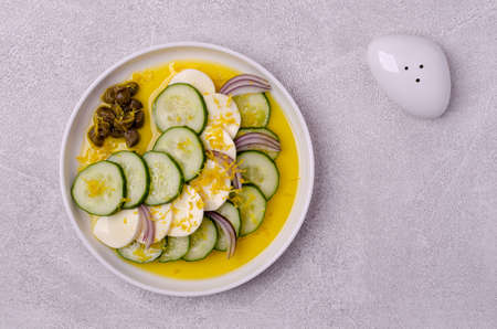 Salad of cucumbers, cheese, capers and lemon zest on a gray background. Top view. Selective focus.の写真素材