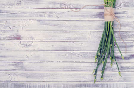 Stems green onion flowers on light wooden boards. Top view. Tinting. Selective focus.の写真素材