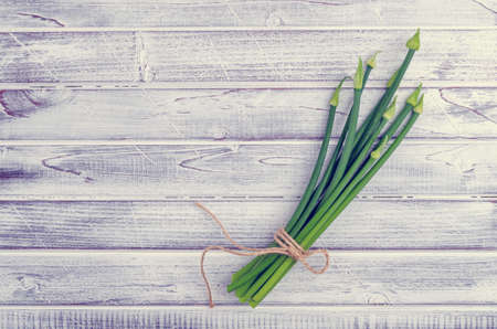 Stems green onion flowers on light wooden boards. Top view. Tinting. Selective focus.の写真素材