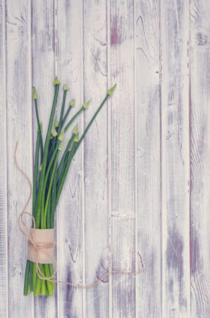Stems green onion flowers on light wooden boards. Top view. Tinting. Selective focus.の写真素材
