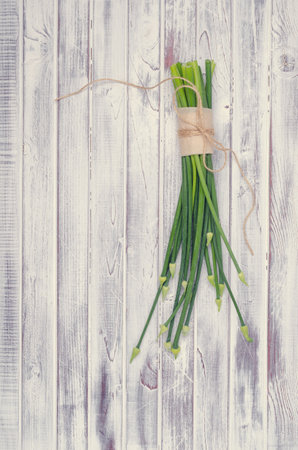 Stems green onion flowers on light wooden boards. Top view. Tinting. Selective focus.の写真素材