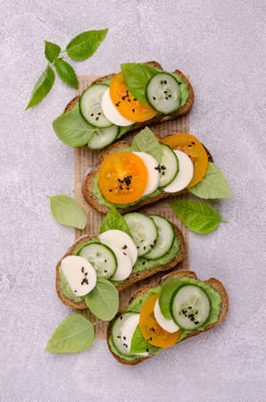 Sandwiches with vegetables, cheese and green sauce on a gray background. Top view.の写真素材