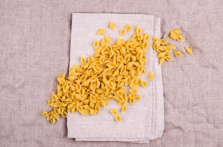 Dry shell pasta on a textile background. Top view. Copy space.